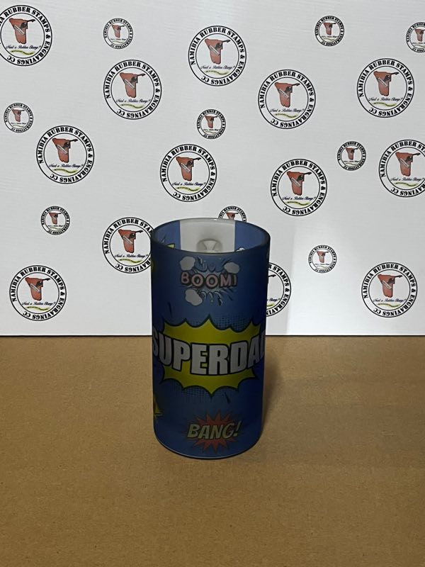 A frosted glass beer mug printed with a comic-style SUPERDAD design