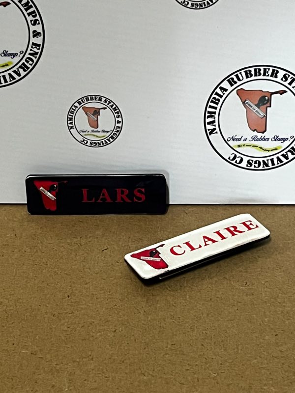 Black and white name badges printed with the Namibia Rubber Stamps logo in red