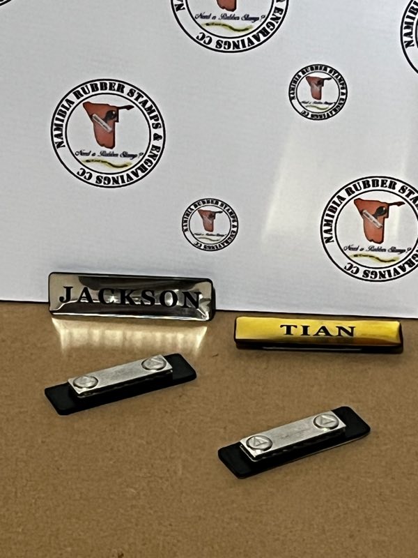Engraved silver and gold name badges shown with their magnetic backing plates