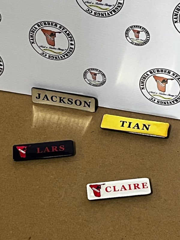Four name badges — silver, gold, and black and white versions printed with the company logo